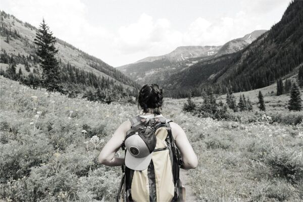 Foto de una persona con una mochila andando por la montaña, sintiéndose feliz en la naturaleza